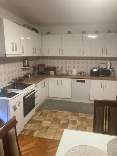 an empty kitchen with white cabinets and a table at Nevade home in Gornji Milanovac