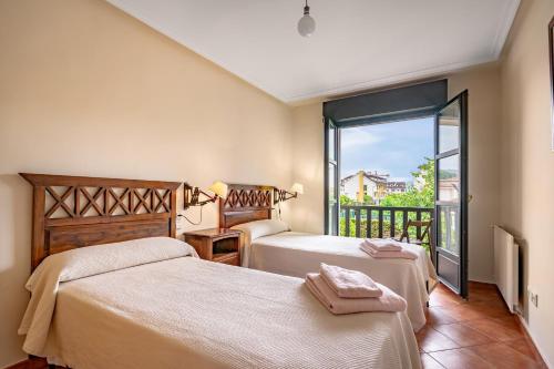 a bedroom with two beds and a balcony at Chalet Picu Fontanielles en Colunga in Colunga