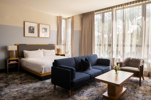 a hotel room with a bed and a blue couch at Clayton Hotel & Members Club - Cherry Creek, Denver in Denver