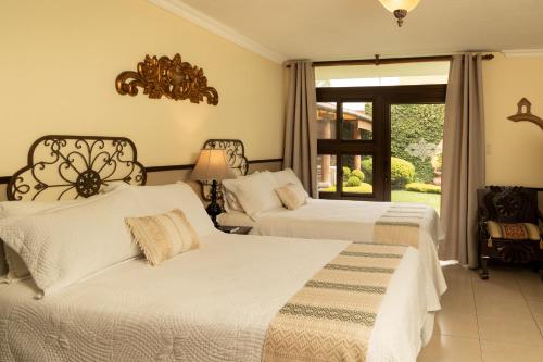 a bedroom with two beds and a window at Hostal Villa Toscana in Guatemala