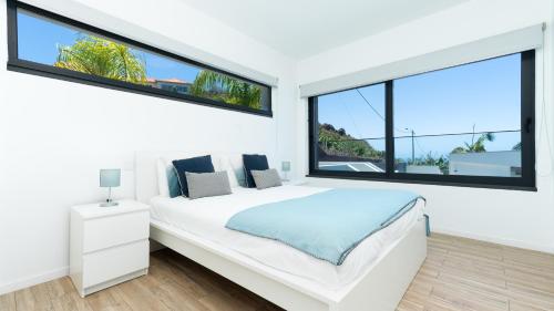 a bedroom with a white bed and large windows at Villa Calhau by LovelyStay in Ponta do Sol