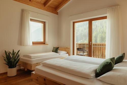 a bedroom with two beds and a window at New - Penthouse Zirm Untermairhof in Selva dei Molini