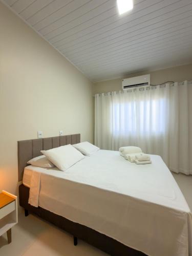 a bedroom with a large white bed and a window at Casa 02 - Aconchegante e cheia de estilo - 5 min do centro in Alta Floresta