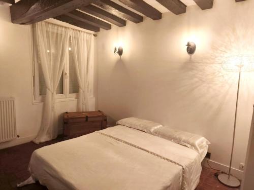 a white bedroom with a bed and a window at Cottage spirit in Normandy - typical studio in Évreux