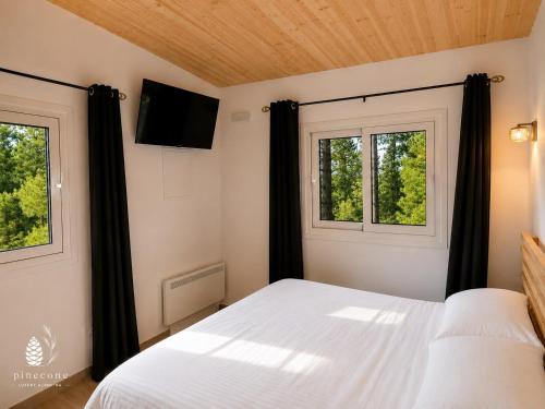 a bedroom with a white bed and two windows at Pinecone Luxury Glamping in Louvaras