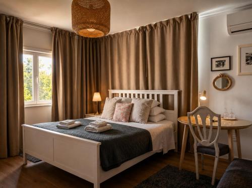 a bedroom with a bed and a table and a window at Casa das Hortênsias - Charming Guest House in Sintra