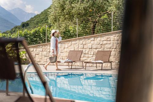 a woman walking by a pool talking on a cell phone at Residence La Vigna in Arco
