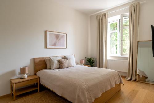 a white bedroom with a large bed and a window at Historic Karaimai Street Balcony Apartment, Trakai, Lithuania in Trakai