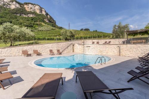a patio with a pool and chairs and a mountain at Residence La Vigna in Arco