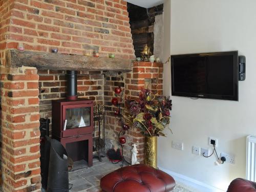 a living room with a brick fireplace with a wood stove at Walnut Cottage in Sproughton