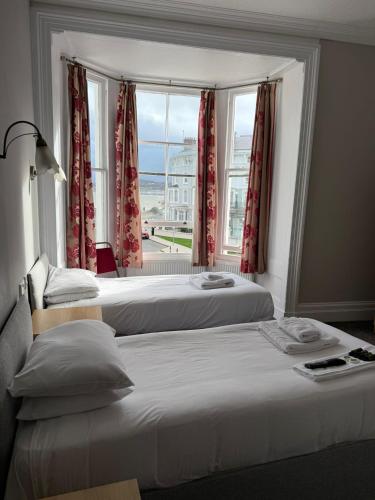 two beds in a room with a window at Baytree Hotel in Llandudno