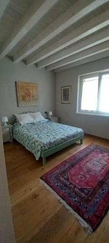 a bedroom with a bed and a rug and a window at Casa 33 in Gardone Riviera