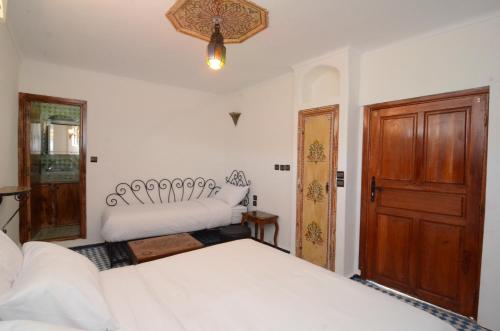 a bedroom with two beds and a wooden door at Le Cèdre D'argent in Fès