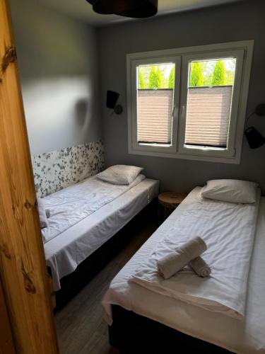 two beds in a room with two windows at Twoje Rydzewo in Rydzewo