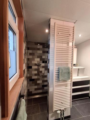 a bathroom with a shower with a towel on a wall at Guesthouse Bij Maud in Barsingerhorn