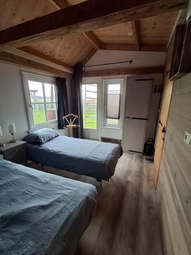 a bedroom with two beds and two windows at Guesthouse Bij Maud in Barsingerhorn