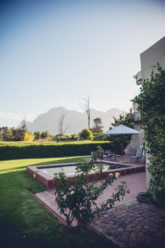 a patio with a table and an umbrella in a yard at Station House Simondium in Simondium