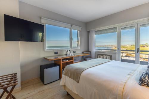 ein Schlafzimmer mit Bett, Schreibtisch und Fenstern in der Unterkunft Hotel Las Rocas in Mar del Plata