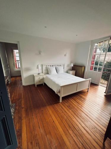 a bedroom with a white bed and a wooden floor at Les gîtes in Daubeuf-Serville
