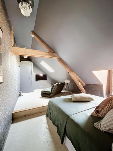 a attic bedroom with a bed and a chair at Chambre d'hôtes Cocotte & Bigoudi in La Ferté-Beauharnais
