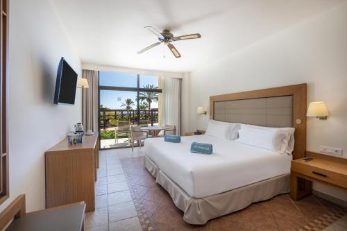 a bedroom with a large white bed and a balcony at Occidental Jandía Royal Level - Adults Only in Morro del Jable