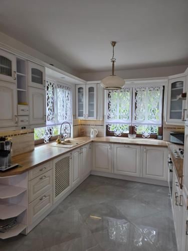 a large kitchen with white cabinets and windows at ŁeboVe ZaCisze Spa & Relax in Łeba