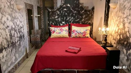 a bedroom with a red bed with a red blanket and pillows at Pousada Rainha das Águas in Ilhéus