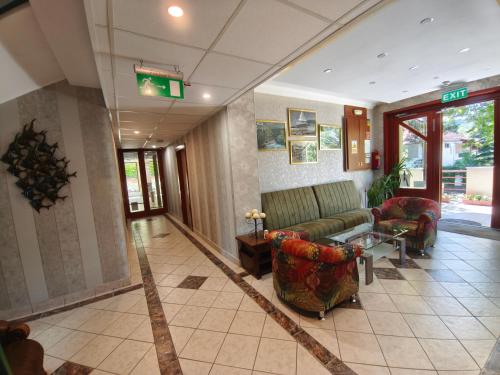 a lobby with a couch and chairs in a building at Fortuna Hotel in Miskolctapolca
