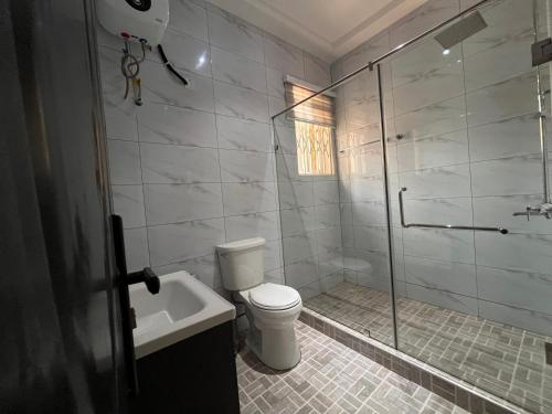 a bathroom with a shower and a toilet and a sink at Modern Three-Bedroom Apartment in Accra