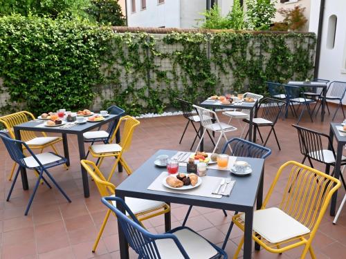 a patio with tables and chairs with food on them at Hotel Scala - Buongiorno! Hotels in Treviso