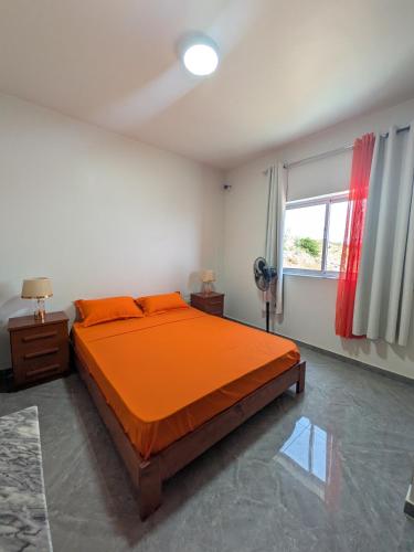 an orange bed in a white room with a window at Mirage in Tarrafal