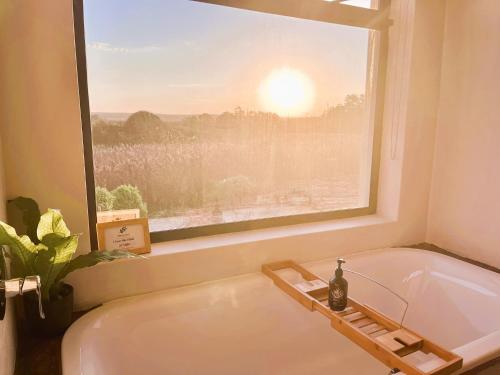 a bath tub in a bathroom with a window at Olive Grove Addo in Addo