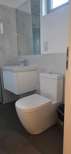 a white bathroom with a toilet and a sink at The Lennox Premier Suites in Accra