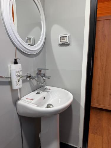 ein Badezimmer mit einem weißen Waschbecken und einem Spiegel in der Unterkunft Lean chalet Sea&Mountain view in Dukat