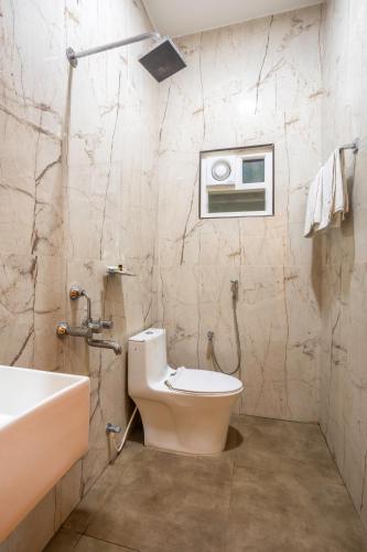 a bathroom with a toilet and a sink and a tub at Hotel Saesha International in Rāmeswaram