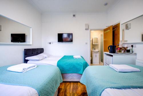 a room with three beds and a tv in it at The City Hotel London in London