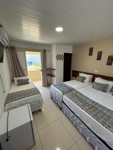 a hotel room with two beds and a balcony at Pousada e Restaurante Império do Marisco in Maragogi