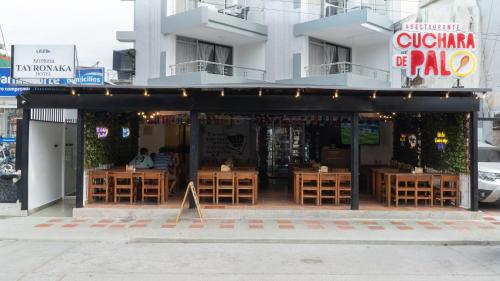 a restaurant with wooden tables in front of a building at Hotel Tayronaka in Santa Marta