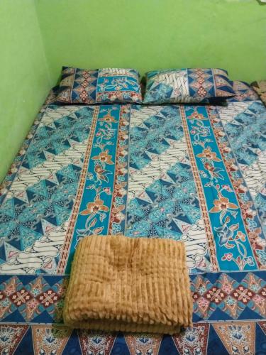 a bed with a quilt and pillows on it at Setro Kariyo Homestay in Bantul