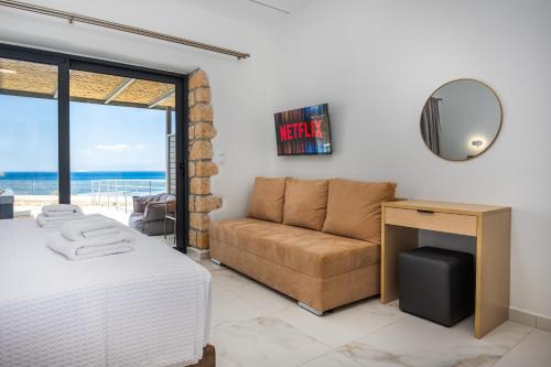 a bedroom with a bed and a couch and a mirror at Summer & Sun in Vathí