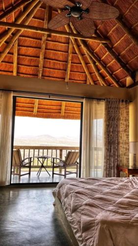 a bedroom with a ceiling fan and a bed and a balcony at Lodge Kapembawé in Benguela