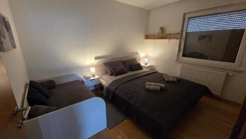 a bedroom with a bed and a couch next to a window at DenVigo in Čakovec