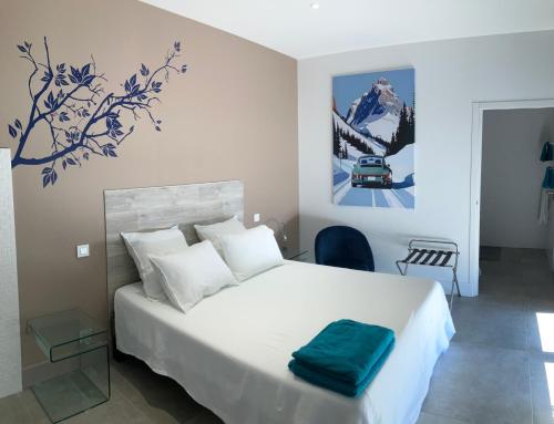 a bedroom with a white bed with a blue painting on the wall at Panoradome - Avec table d'hôtes sur réservation - Climatisé in Saint-Maurice