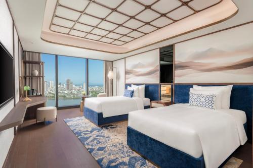 a hotel room with two beds and a large window at TUI BLUE Han River in Danang