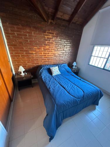 a bedroom with a blue bed in a brick wall at Solymar Alojamiento in Puerto Madryn