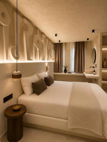 a bedroom with a large white bed and a table at Ethos Suites in Agios Prokopios