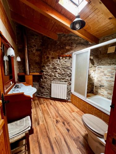 a bathroom with a toilet and a stone wall at El Rincón de la Rosa in Brugos de Fenar
