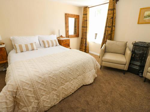 a bedroom with a bed and a chair and a window at Arch Mews Cottage in Barnard Castle