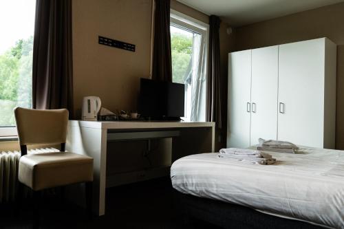 a bedroom with a bed and a desk and a window at Budget Hostel De Elderschans in Aardenburg