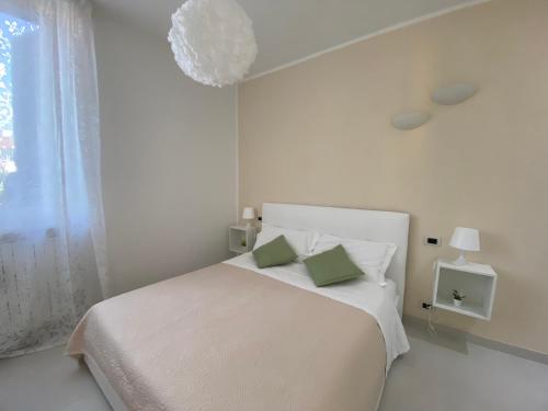 a white bedroom with a bed with two green pillows at Il Rifugio in Sulmona